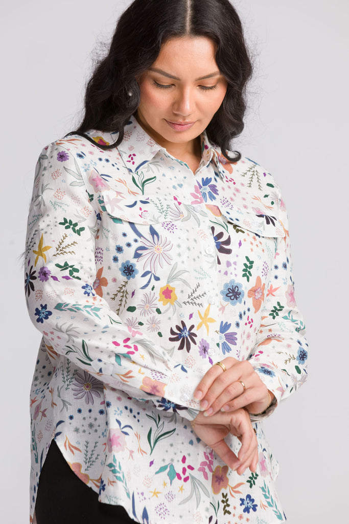 Woman wearing a colorful floral shirt against a plain background