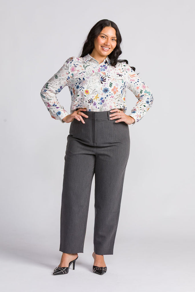 Woman wearing a floral blouse and gray pants on a white background