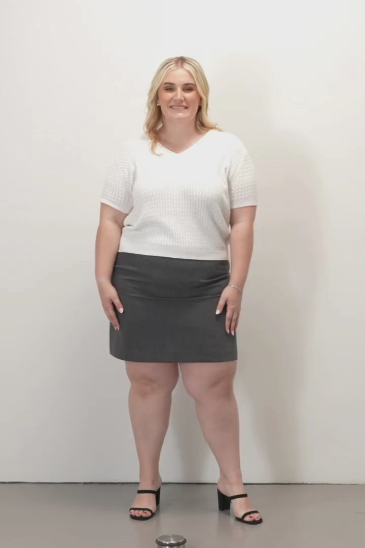 Pippa Tailored Short Skirt - Charcoal -Woman wearing a gray skirt and white top on a plain background.